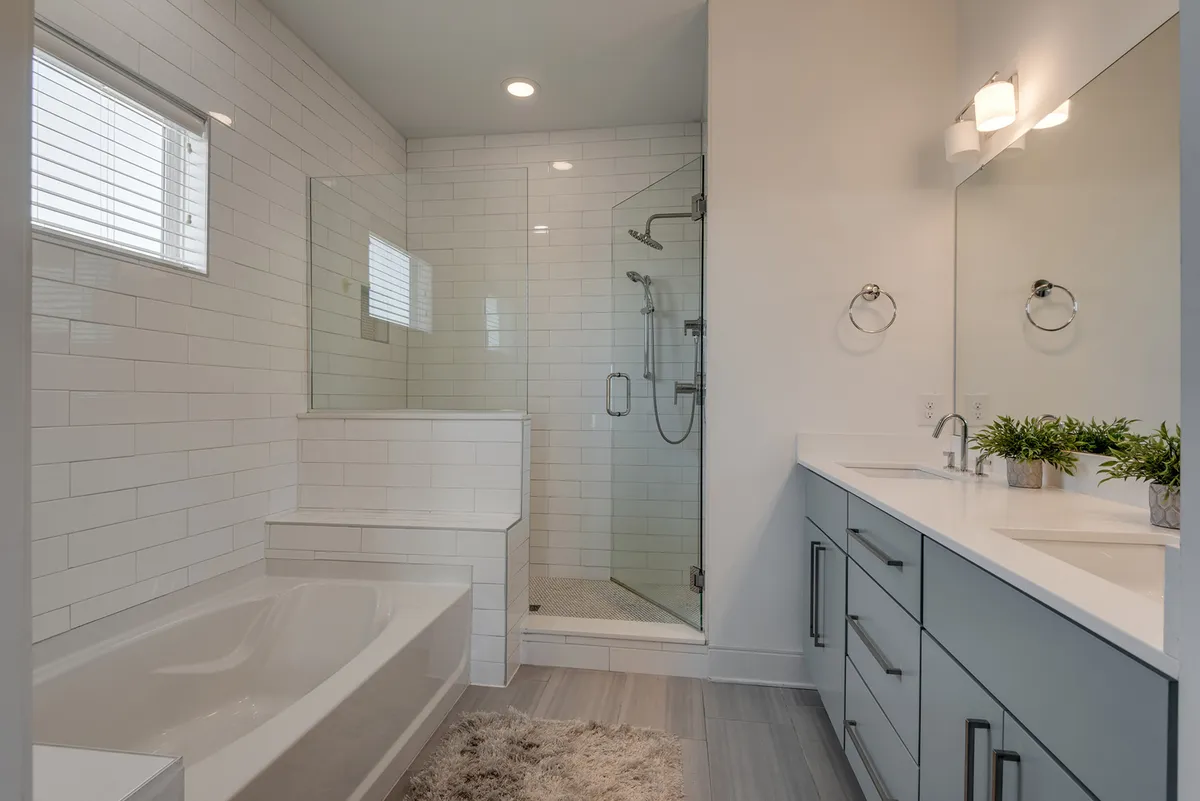 A modern en-suite bathroom with a large bathtub, walk-in shower, double vanity, and mirrors, all set in a tranquil and inviting style. The space is bright and exudes a spa-like comfort.