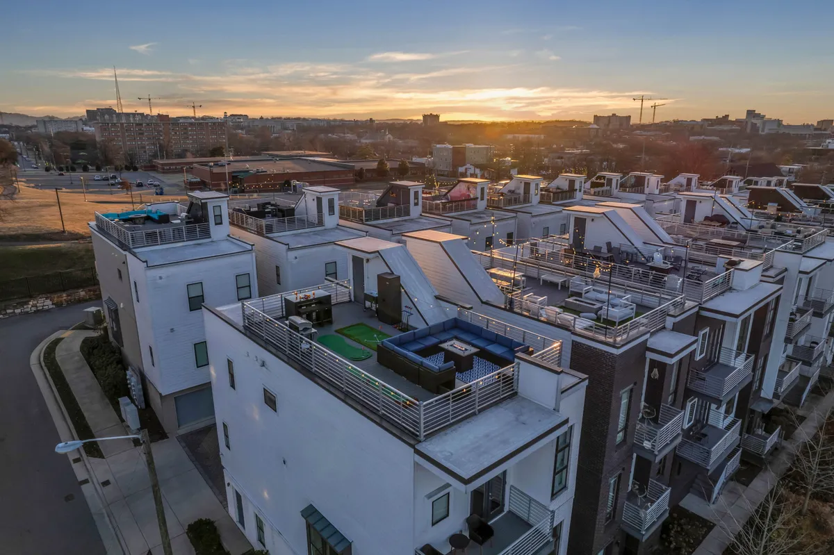 A stylish rooftop space with modern architectural lines, outdoor dining areas, and a vibrant sunset sky. The area is designed for gatherings, relaxation, and enjoying panoramic city views, perfect for informal meetings or evening socializing after a day’s work.